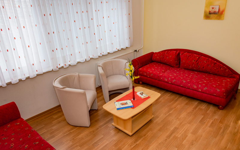 Gästewohnung Radebeuler Str. 6b - rote Couch mit weißen Sesseln und Clubtisch